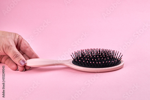 woman take a pink hairbrush isolated on a pink coral background with space. beauty hair accessory for hairstyle.