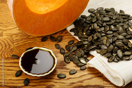 Dark unrefined pumpkin oil, pumpkin seeds and a pumpkin slice 