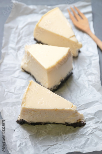 Creamy cheesecake with chocolate cookies slice on baking paper with black tray.