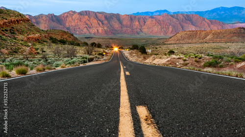 road in the desert of Utah shot low angle in the middle of the road with rocky red mountains as background 