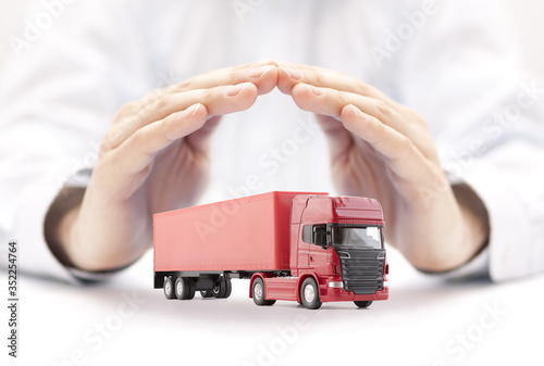 Red long truck with a trailer protected by hands