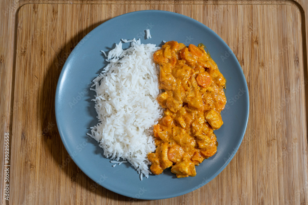 Plate of white rice with chicken and curry sauce on a wooden table. Plate of white rice with chicken and curry sauce on a wooden table.