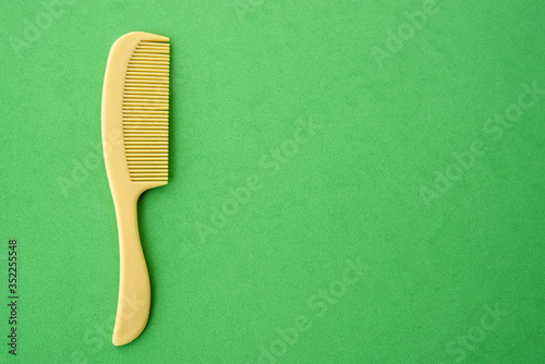 children's plastic hair comb yellow, green background close-up