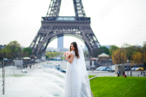 Beautiful bride in rich wedding dress whirls on the square before the Eiffel Tower