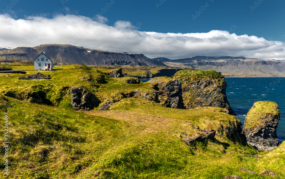 Wonderful Sunny Seascape of Iceland. Amazing summer view of fishing village of Arnarstapi with Alone house in Iceland. Tipical Sunny Scenery with basalt rocks formation on coast. Snaefellsnes, Iceland