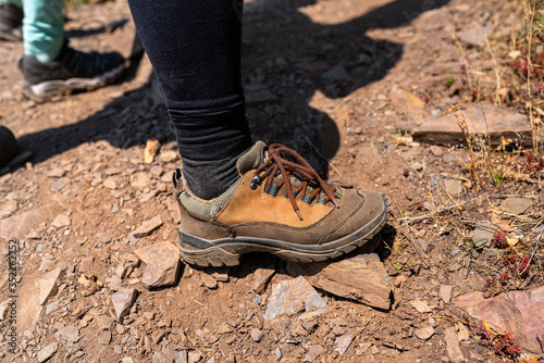 A woman standing in specialized, leather, mountain climbing shoes on a stony, slate surface.