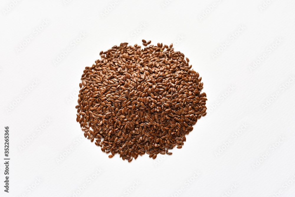 A pile of brown flax or flaxseed on a white background. View from above. A pile of brown flax or flaxseed on a white background. View from above.