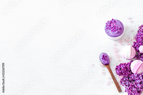 Background Spa composition for body care on a light wooden background with lilac flowers.