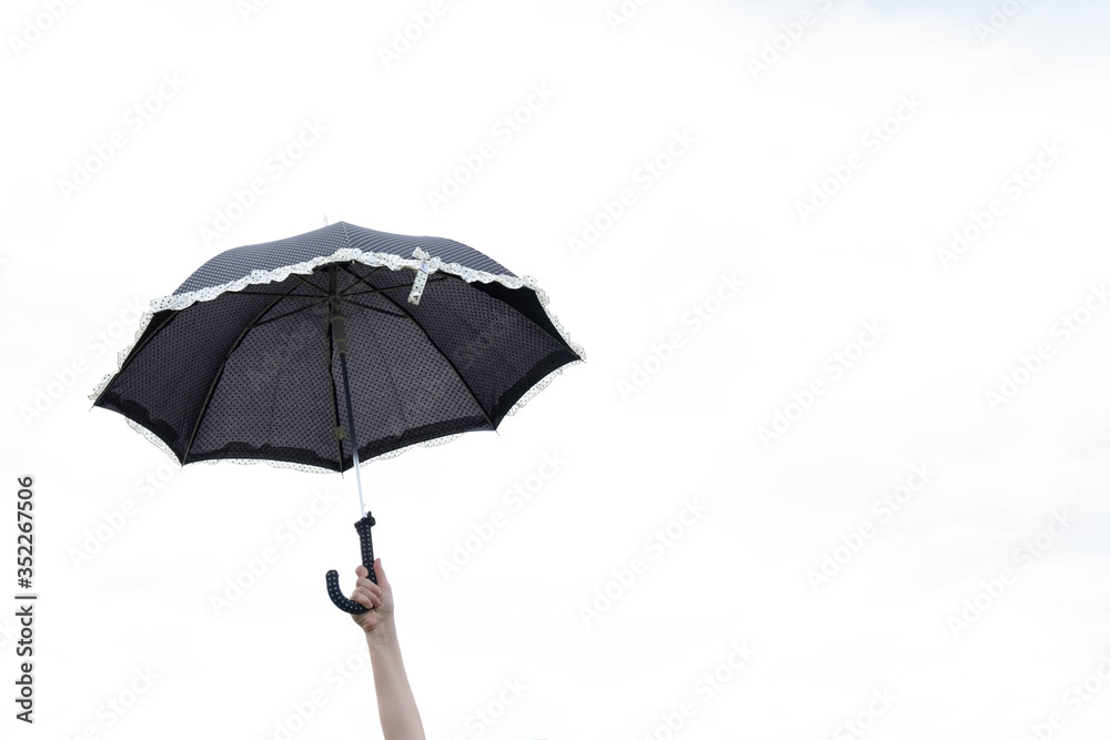 black umbrella in the hand of a little girl on a white sky
