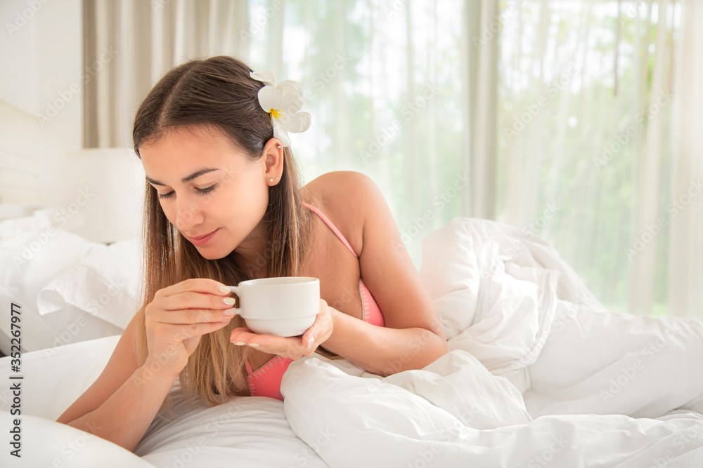 Young beautiful woman drinking a Cup of coffee in bed.