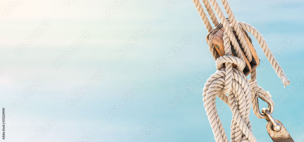 Sailing boat pulley, block and tackle with moored nautical rope. Panoramic water nautic background with copy space. - obrazy, fototapety, plakaty 