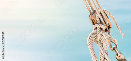 Sailing boat pulley, block and tackle with moored nautical rope. Panoramic water nautic background with copy space.