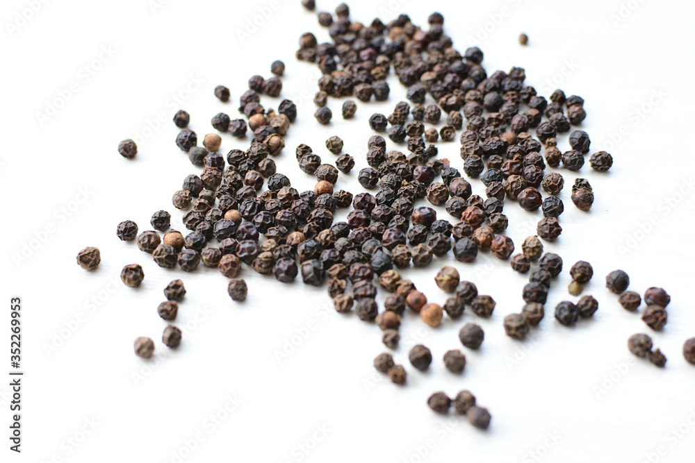 Black peppercorns in bowls on white wooden background Black peppercorns in bowls on white wooden background