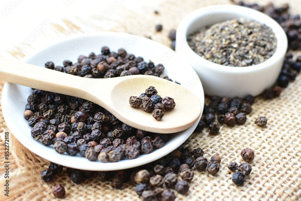 Black peppercorns in bowls on white wooden background Black peppercorns in bowls on white wooden background