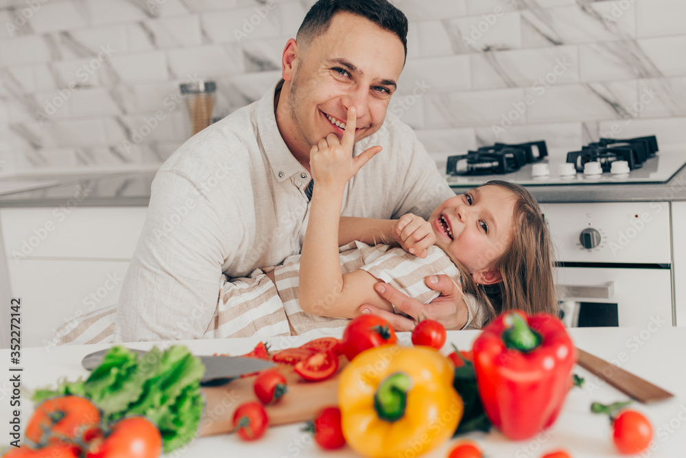 Father's day. Dad and his child daughter are cooking and having fun together in the kitchen. Family holiday. Father's day. Dad and his child daughter are cooking and having fun together in the kitchen. Family holiday.