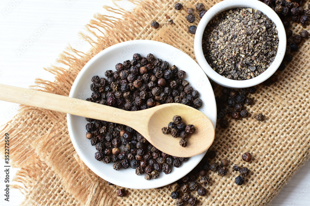 Black peppercorns in bowls on white wooden background Black peppercorns in bowls on white wooden background