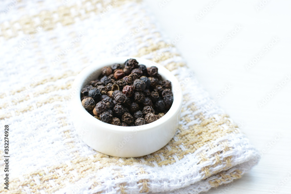 Black peppercorns in bowls on white wooden background Black peppercorns in bowls on white wooden background