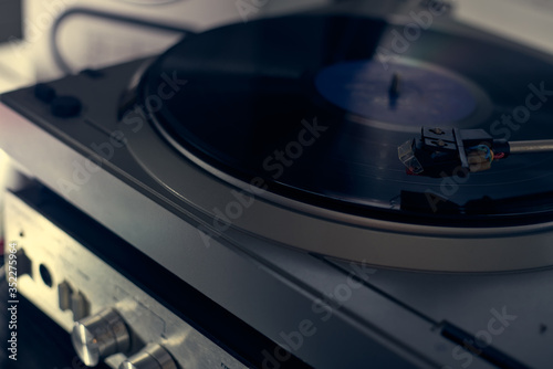 The vinyl needle reads the music from the record on a vinyl player. Old school. musical atmosphere. Old player and analog music. subject photo. the song plays