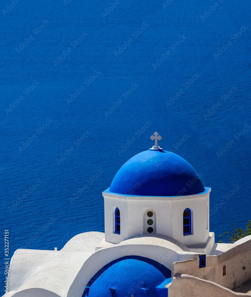 White church with blue dome against blue sea background. Oia Santorini, Greece.