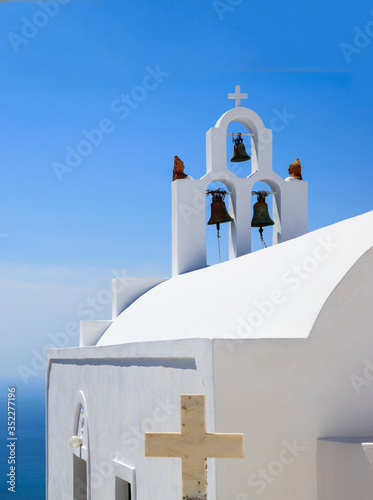 Santorini, Greece. White church and bells against blue sea and sky background.