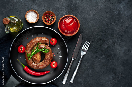 grilled spiral sausage with spices in a pan on a stone background with copy space for your text