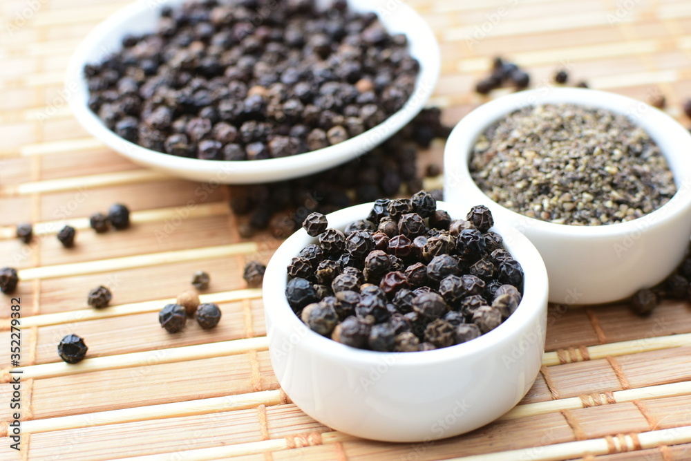 Whole and ground black peppercorns on white wooden background Whole and ground black peppercorns on white wooden background