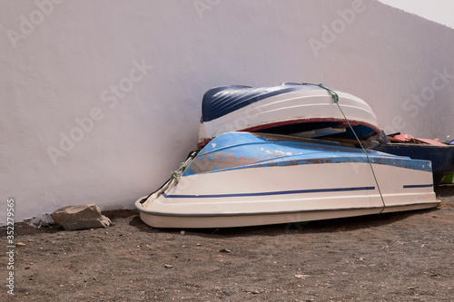 Two small boats saved after fishing next to a white wall