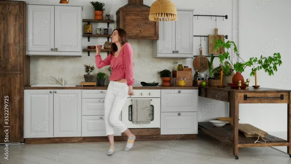 Cute girl puts a frying pan in the sink while dancing in the kitchen Cute girl puts a frying pan in the sink while dancing in the kitchen