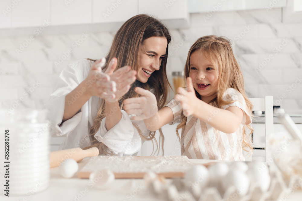 Happy mother with her daughter preparing dough and having fun in kitchen. Cooking homemade food. Happy mother with her daughter preparing dough and having fun in kitchen. Cooking homemade food.