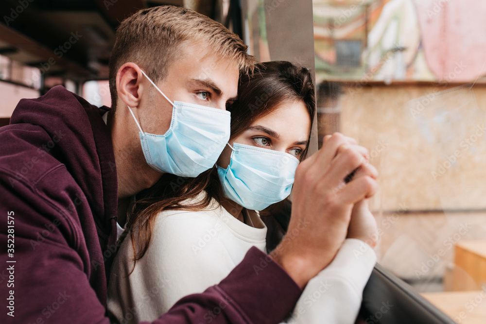 Young couple in protective masks at home in quarantine covid-19