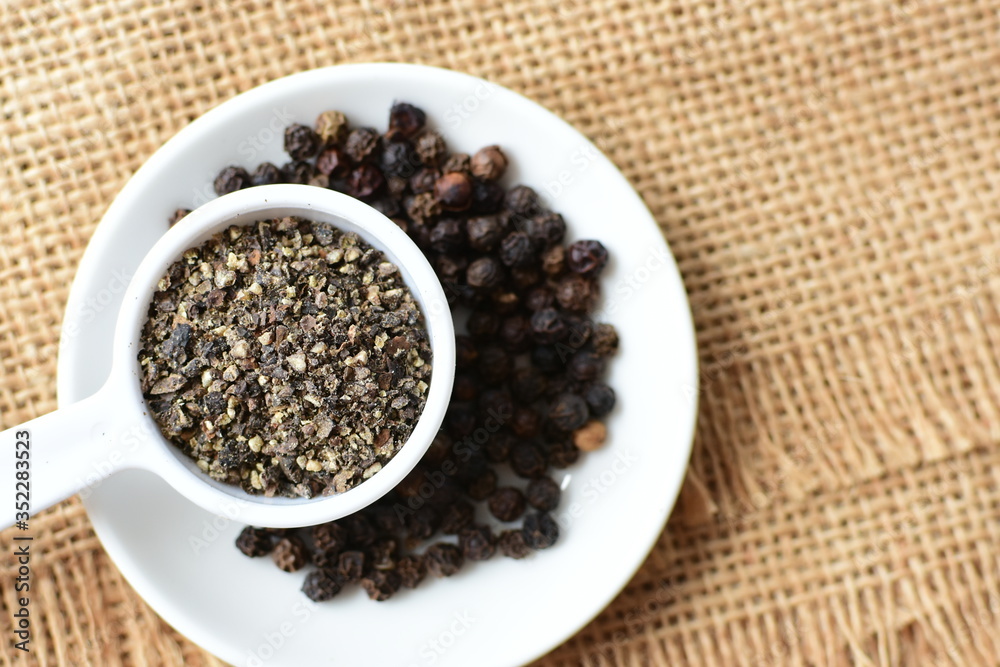 Whole and ground black peppercorns on white wooden background Whole and ground black peppercorns on white wooden background