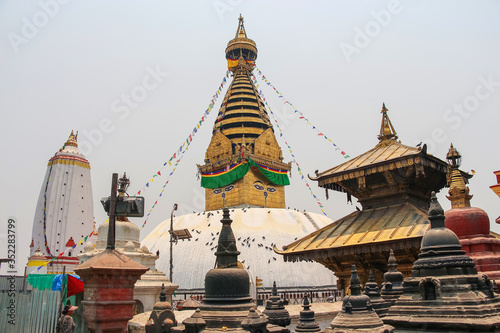 View of buddhist Swayambhunath stupa, also known among tourists as Monkey Temple, with traditional "Eyes of Buddha" painting and hinduist Harati Ajima Temple. Selective focus.