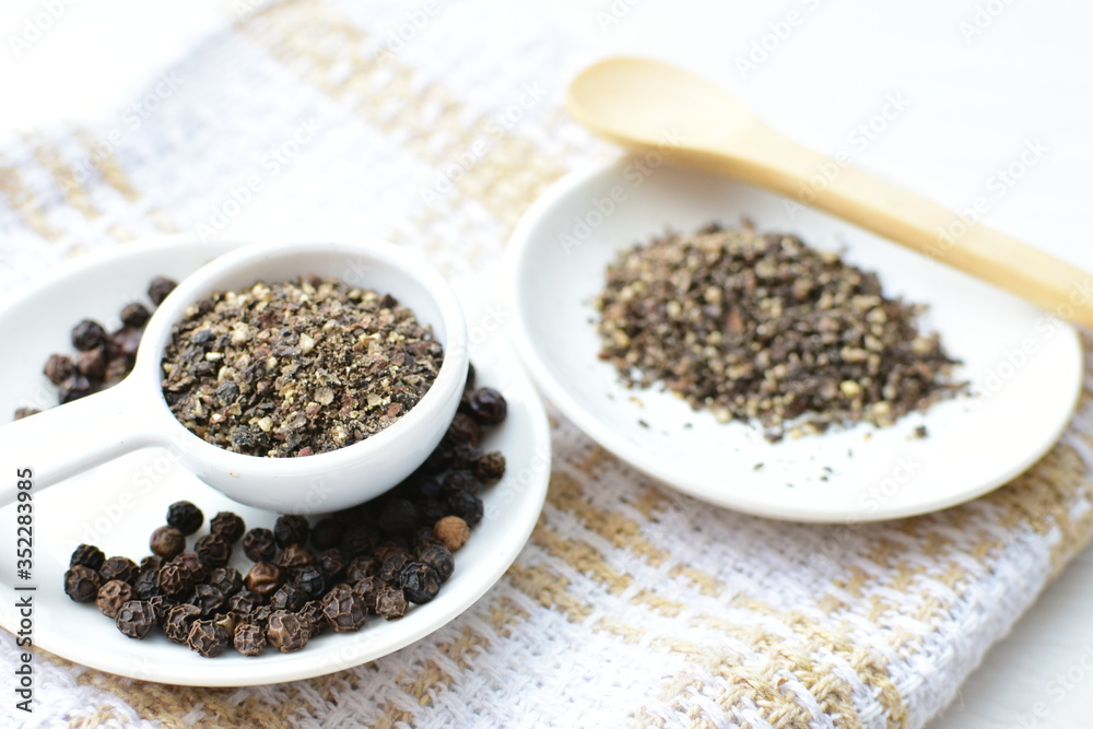Whole and ground black peppercorns on white wooden background Whole and ground black peppercorns on white wooden background