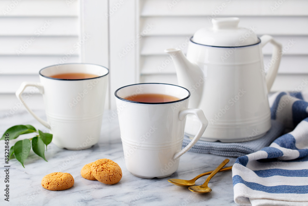 Tea in mugs with teapot on marble background. Close up. Tea in mugs with teapot on marble background. Close up.