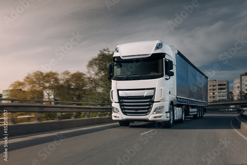 Wallpaper Mural Semi-truck with cargo trailer driving at the city streets. Fast moving truck. Lorry driver go fast at the city centre Torontodigital.ca