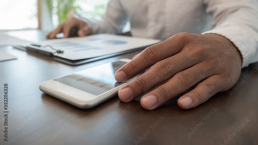 Businessman using smartphone to checking the company performance chart in the office. Business concept. Businessman using smartphone to checking the company performance chart in the office. Business concept.