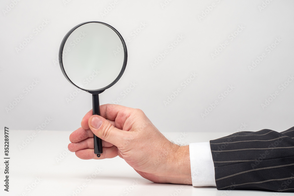 Hand of a man with a magnifying glass close-up. Magnifying glass Hand of a man with a magnifying glass close-up. Magnifying glass