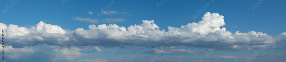 Panorama with white, fluffy Cumulus clouds on a blue sky in the daytime
