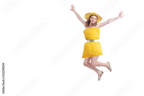 Woman in yellow pillow dress and hat happy jumps, flies and smiles in flight on white background. End of quarantine. Freedom and travel. Pillow Challenge due to stay home isolation. Copy space.
