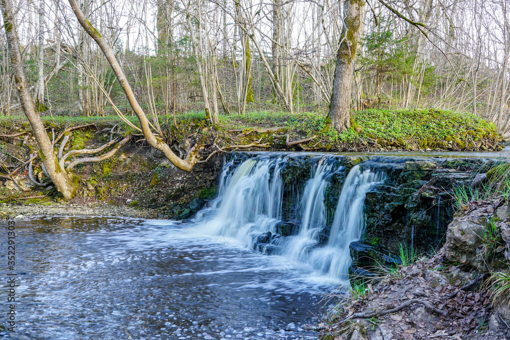 beautiful view in spring of a waterfall in a small river beautiful view in spring of a waterfall in a small river
