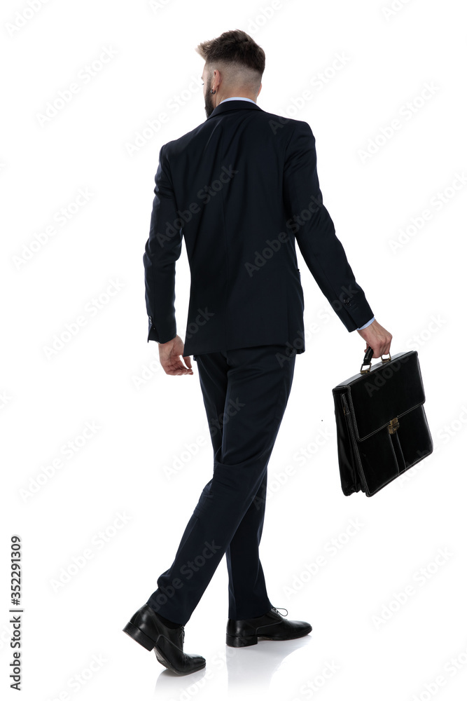 back view of young businessman holding suitcase and walking back view of young businessman holding suitcase and walking