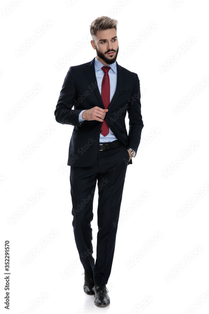 confident young businessman adjusting coat and walking