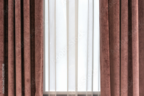 Brown velor curtains and white tulle on the window in the living room.