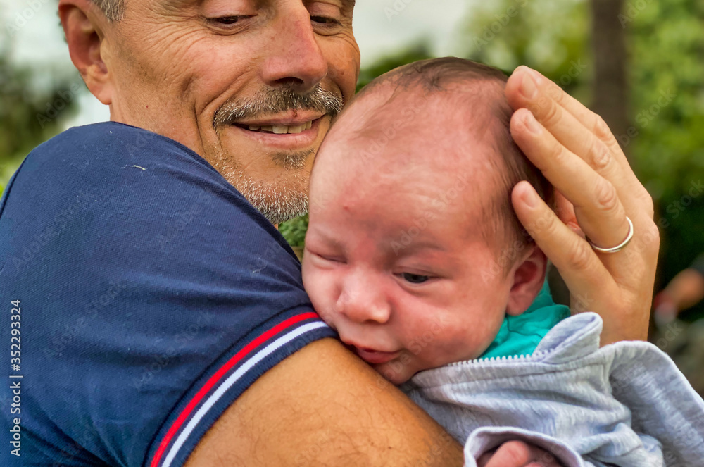 Fototapeta premium Man holding his newborn baby outdoor