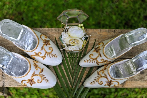 a pair of white Javanese bridal shoes with gold embroidery thread ornaments photo