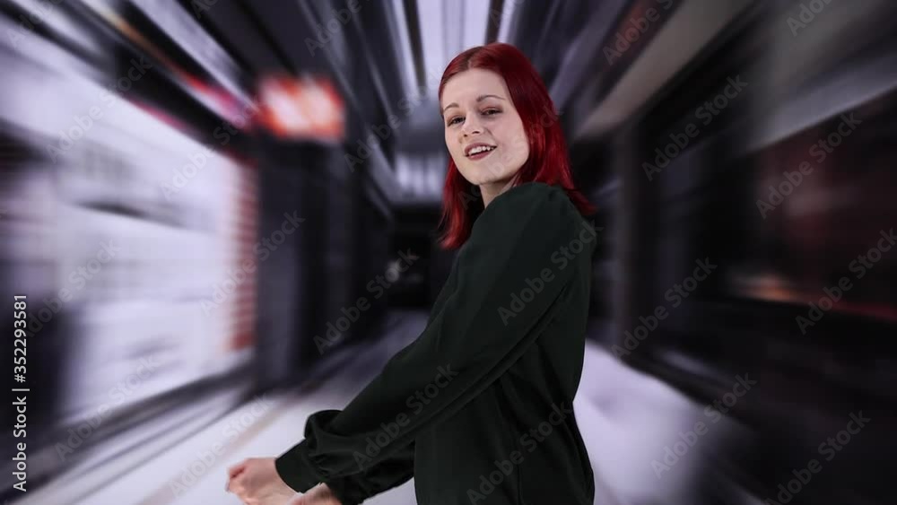 Eine junge hübsche Frau mit kurzen roten Haaren tanzt dynamisch auf einer Straße. 