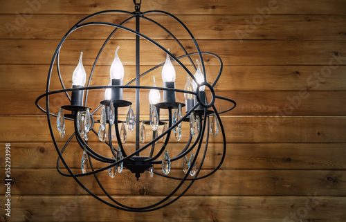 Black metal chandelier with bulb-candles and crystal pendants.