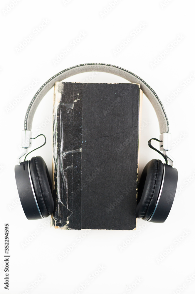 Audio book concept. headphones with book on white background. Listening to book. Modern education. Copyspace. Audio book concept. headphones with book on white background. Listening to book. Modern education. Copyspace.