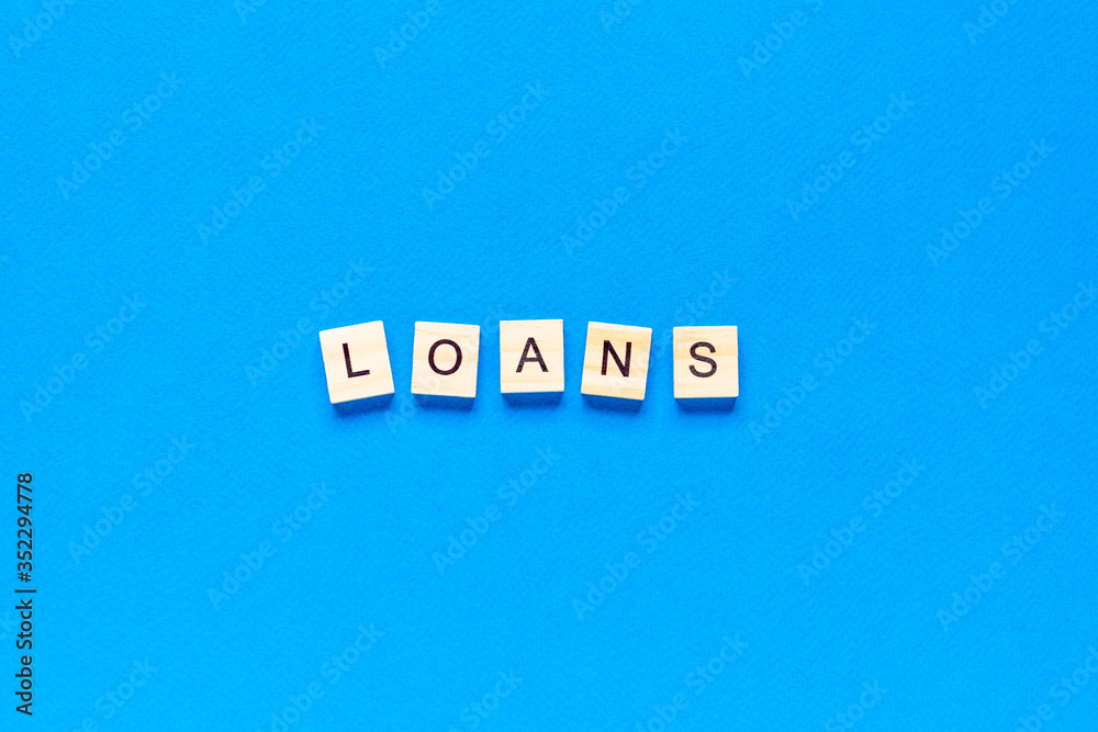 Obraz premium loans inscription in wooden letters on a blue background, flat layout, top view, banner