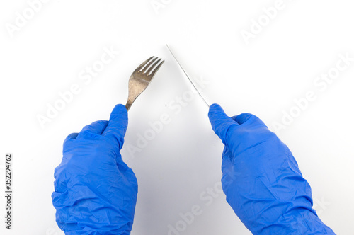 Hands in gloves keeping fork and knife over white background top view. Copy space for your text